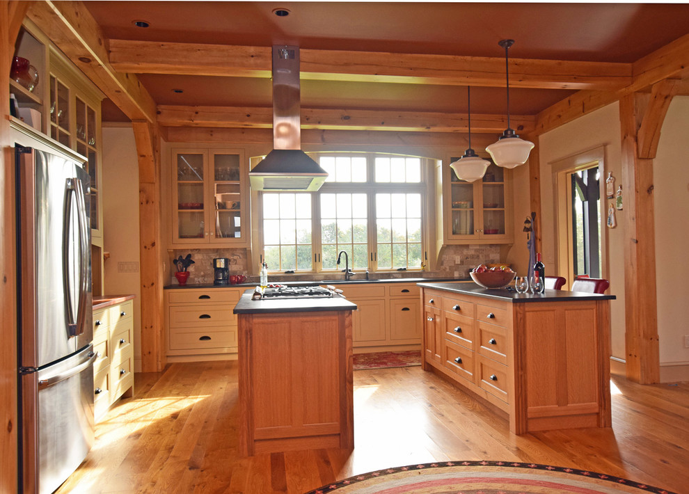 Example of a large farmhouse l-shaped light wood floor open concept kitchen design in Burlington with a single-bowl sink, beaded inset cabinets, medium tone wood cabinets, soapstone countertops, beige backsplash, stone tile backsplash, stainless steel appliances and two islands