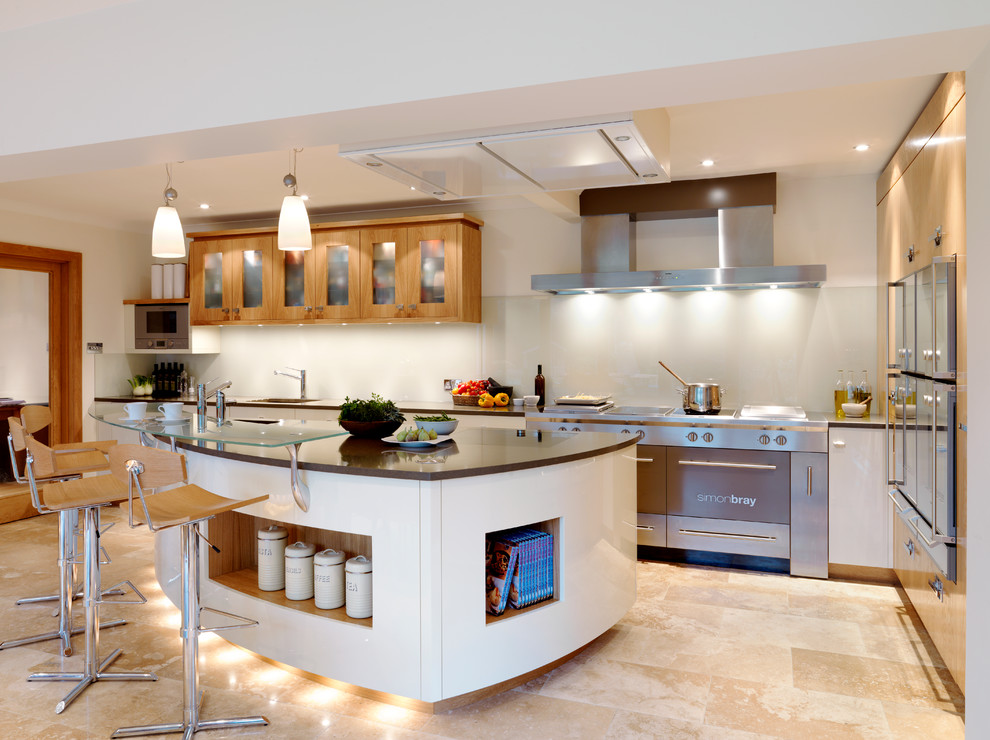 This is an example of a large contemporary kitchen in London with a built-in sink, flat-panel cabinets, quartz worktops, white splashback, stainless steel appliances, travertine flooring and a breakfast bar.