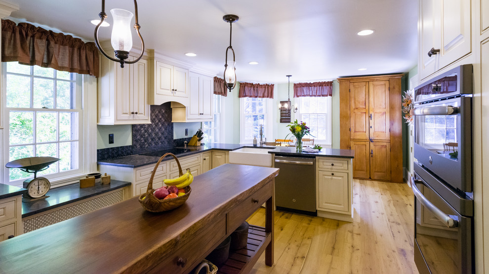 Example of a country light wood floor kitchen design in Philadelphia with granite countertops, black backsplash and an island