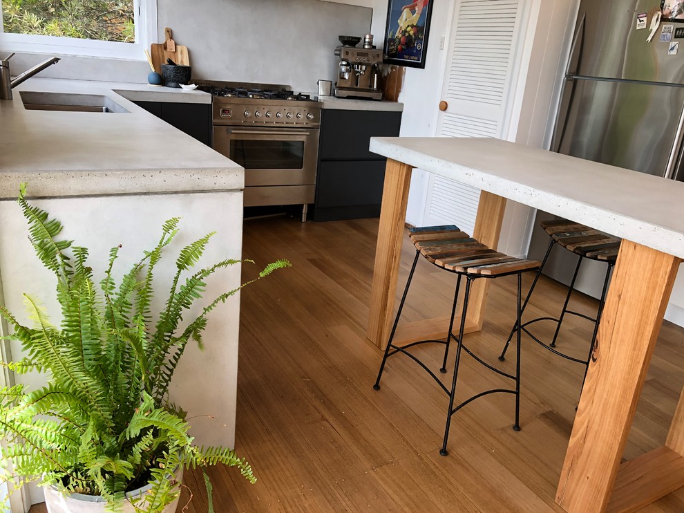 Идея дизайна: угловая кухня-гостиная среднего размера в современном стиле с серым фартуком, островом, столешницей из бетона и серой столешницей