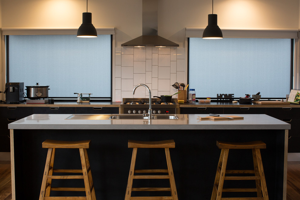 Modern inredning av ett mellanstort grå linjärt grått kök och matrum, med svarta skåp, bänkskiva i betong och en köksö
