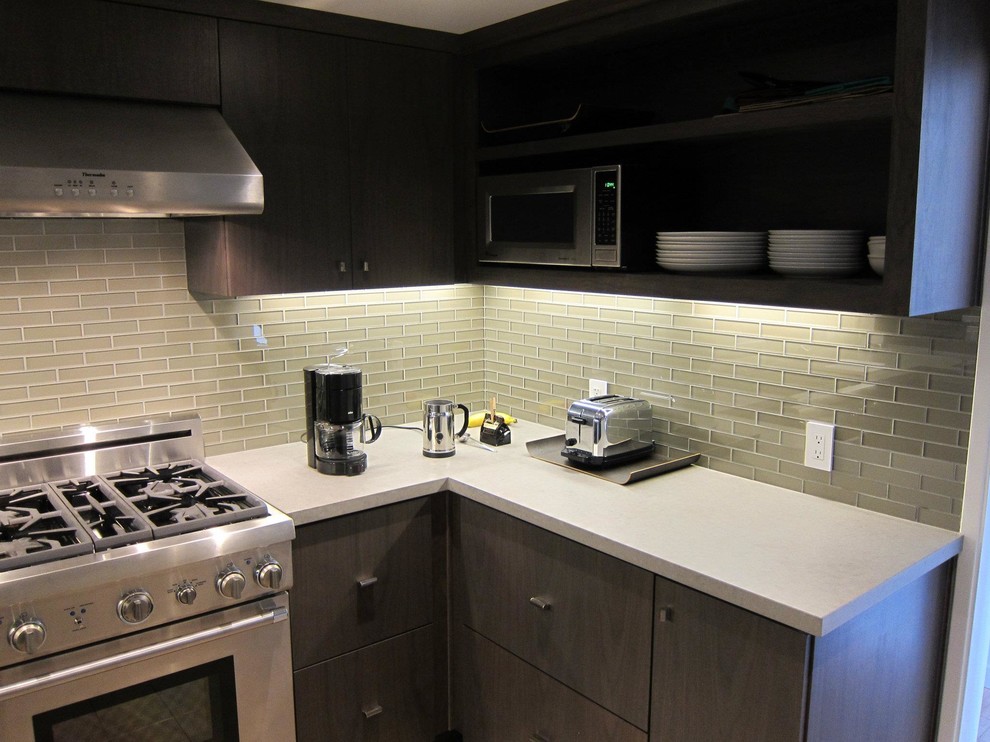 Exempel på ett avskilt, stort modernt u-kök, med en undermonterad diskho, släta luckor, skåp i mörkt trä, grönt stänkskydd, stänkskydd i glaskakel, rostfria vitvaror och en halv köksö