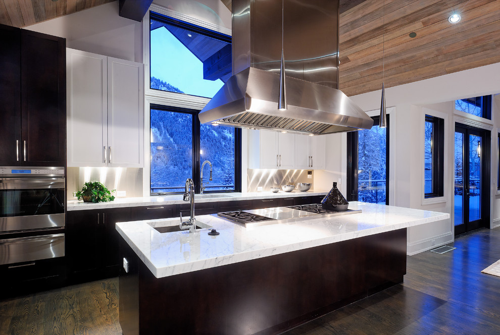 Diseño de cocina rústica abierta con electrodomésticos de acero inoxidable, fregadero bajoencimera, puertas de armario blancas y salpicadero metalizado