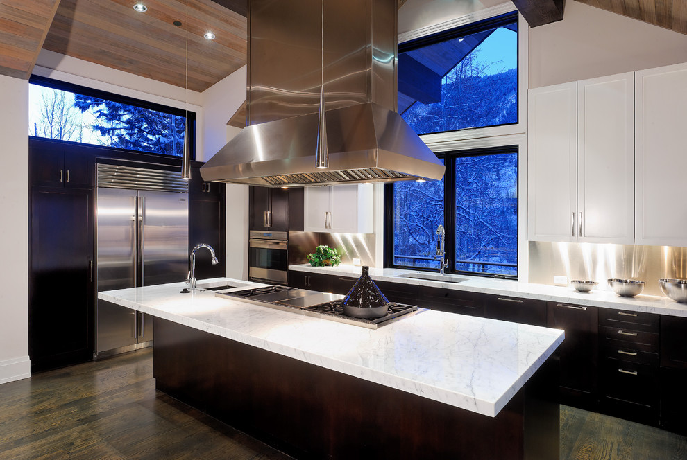 Rustic kitchen in Denver with stainless steel appliances, white cabinets and metallic splashback.