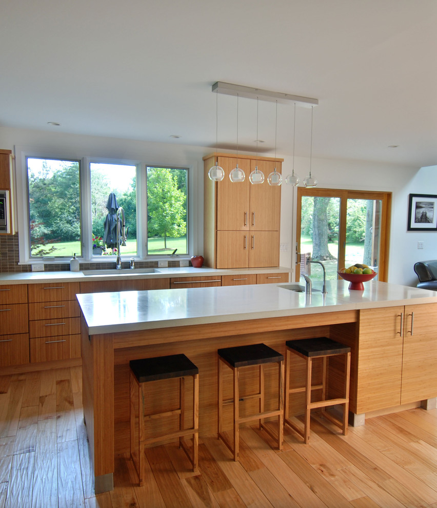 Idee per un cucina con isola centrale design con ante in legno chiaro, top in quarzo composito e parquet chiaro