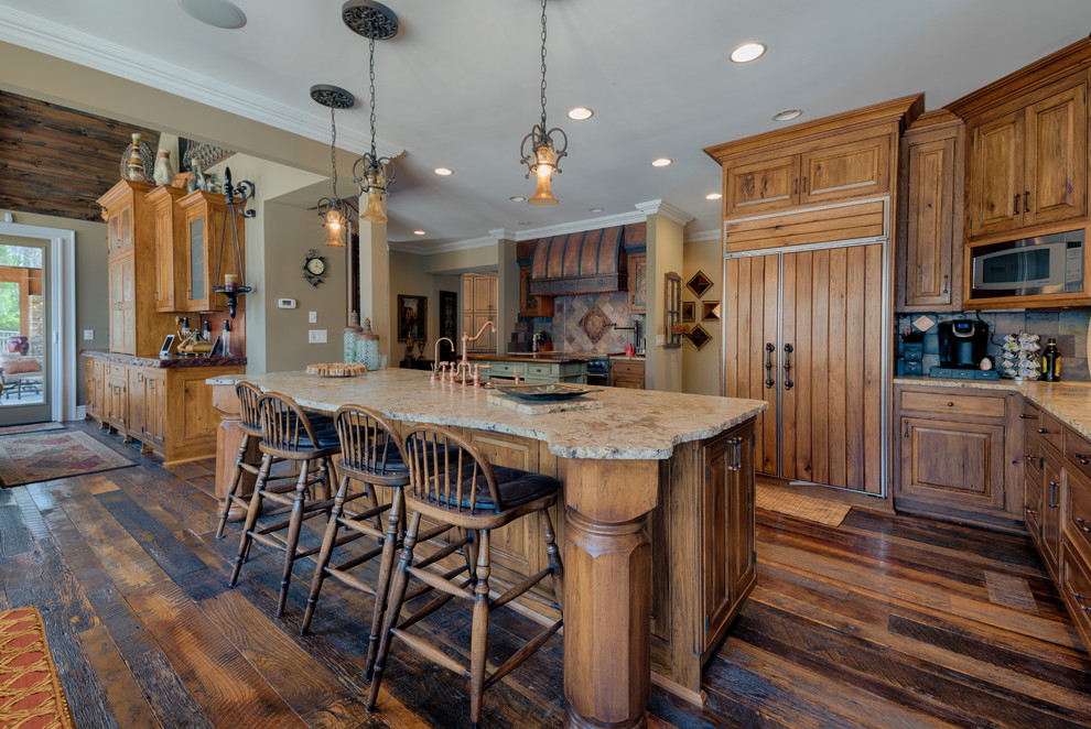 Inspiration for a l-shaped dark wood floor open concept kitchen remodel in Atlanta with raised-panel cabinets, dark wood cabinets, paneled appliances, beige countertops, multicolored backsplash and two islands