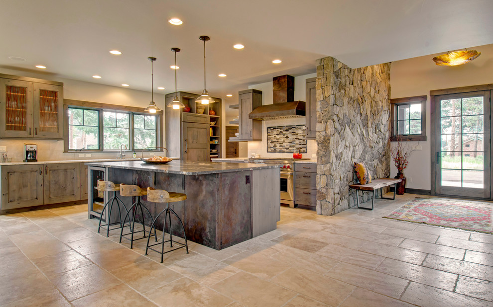 Cette image montre une cuisine chalet en L et bois foncé avec un placard avec porte à panneau encastré, un électroménager en acier inoxydable, îlot et un sol beige.