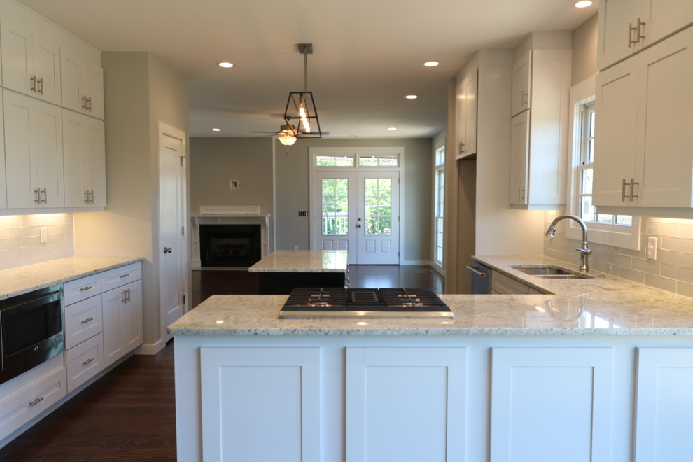 Klassische Wohnküche mit weißen Schränken, Granit-Arbeitsplatte, Küchengeräten aus Edelstahl, braunem Holzboden und Kücheninsel in Nashville