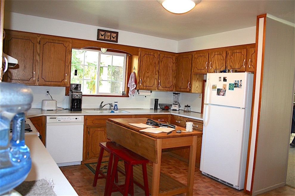Bild på ett avskilt, litet vit vitt u-kök, med en dubbel diskho, släta luckor, skåp i mellenmörkt trä, laminatbänkskiva, vitt stänkskydd, vita vitvaror, vinylgolv och orange golv