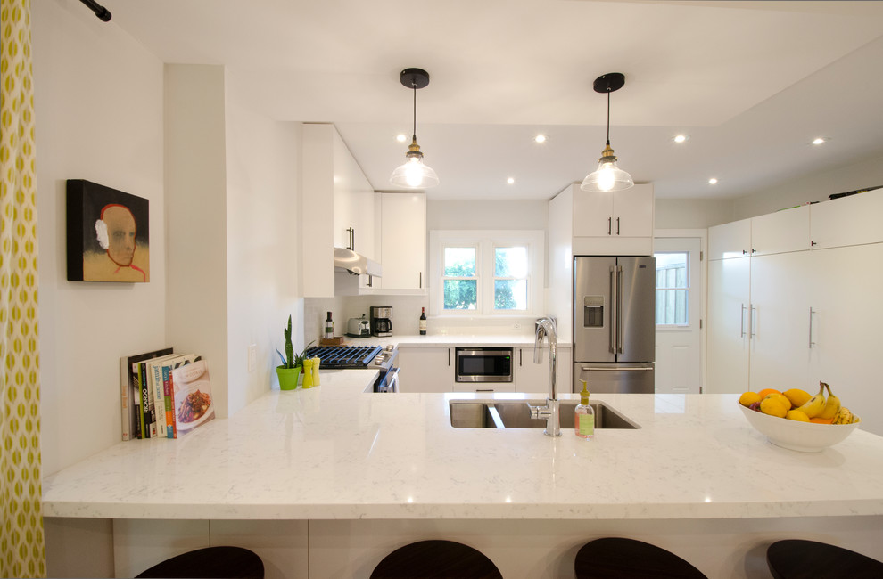 Inspiration for a mid-sized contemporary u-shaped medium tone wood floor and brown floor eat-in kitchen remodel in Toronto with a double-bowl sink, flat-panel cabinets, white cabinets, quartz countertops, white backsplash, subway tile backsplash, stainless steel appliances and a peninsula