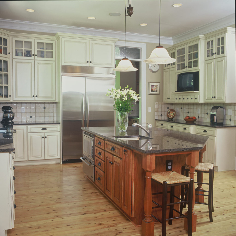 Klassische Küche in U-Form mit profilierten Schrankfronten, weißen Schränken, bunter Rückwand und Küchengeräten aus Edelstahl in Atlanta