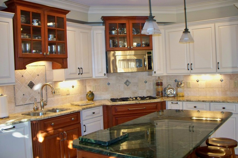 Mid-sized elegant l-shaped bamboo floor enclosed kitchen photo in Columbus with a double-bowl sink, raised-panel cabinets, white cabinets, granite countertops, beige backsplash, travertine backsplash, white appliances and an island