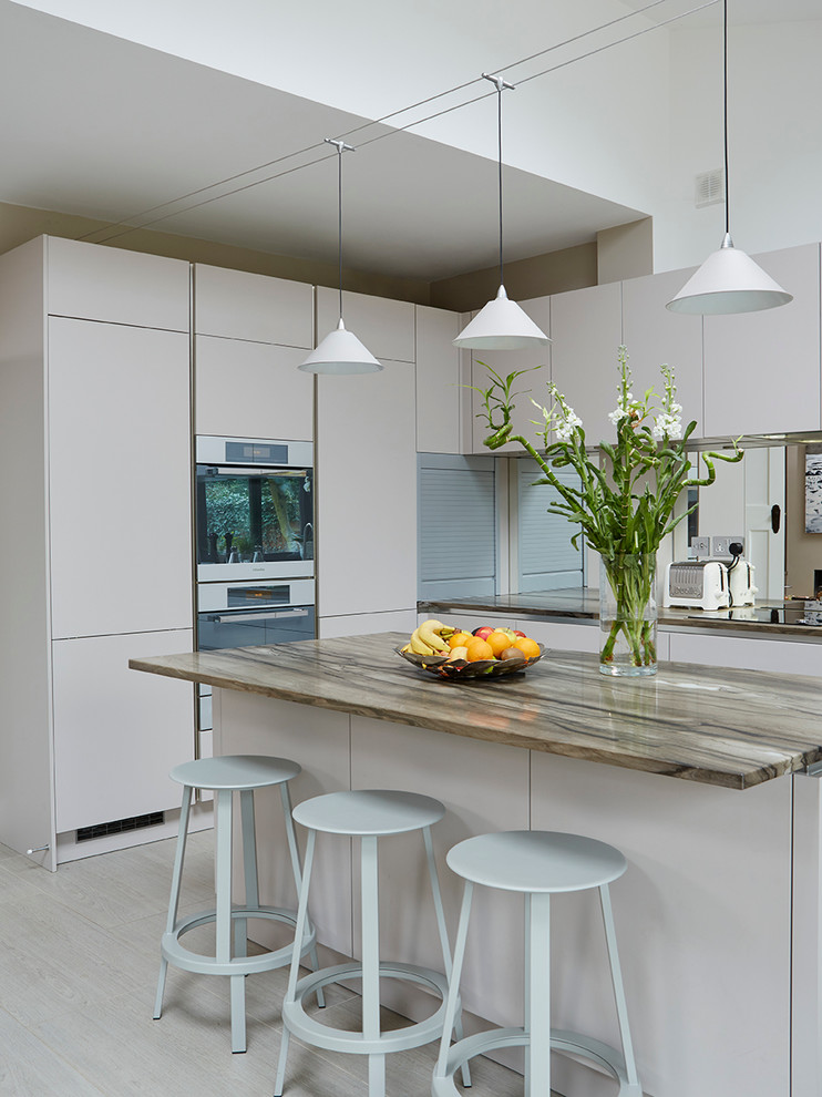 Photo of a medium sized contemporary open plan kitchen in London with a double-bowl sink, white cabinets, granite worktops, metallic splashback, stainless steel appliances, porcelain flooring and an island.