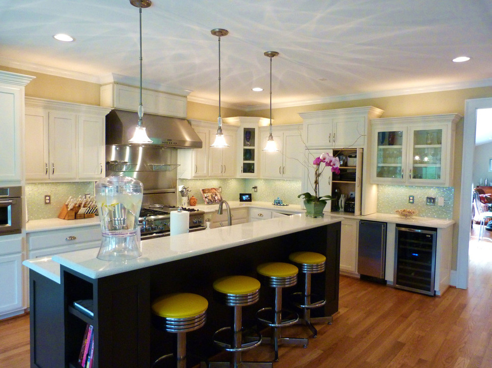 This is an example of a medium sized traditional l-shaped open plan kitchen in Raleigh with a submerged sink, white cabinets, stainless steel appliances, an island, shaker cabinets, quartz worktops, green splashback, mosaic tiled splashback and medium hardwood flooring.