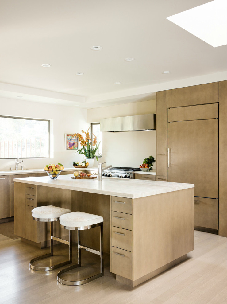 Moderne Küche in L-Form mit Unterbauwaschbecken, flächenbündigen Schrankfronten, Elektrogeräten mit Frontblende, hellem Holzboden und Kücheninsel in San Francisco