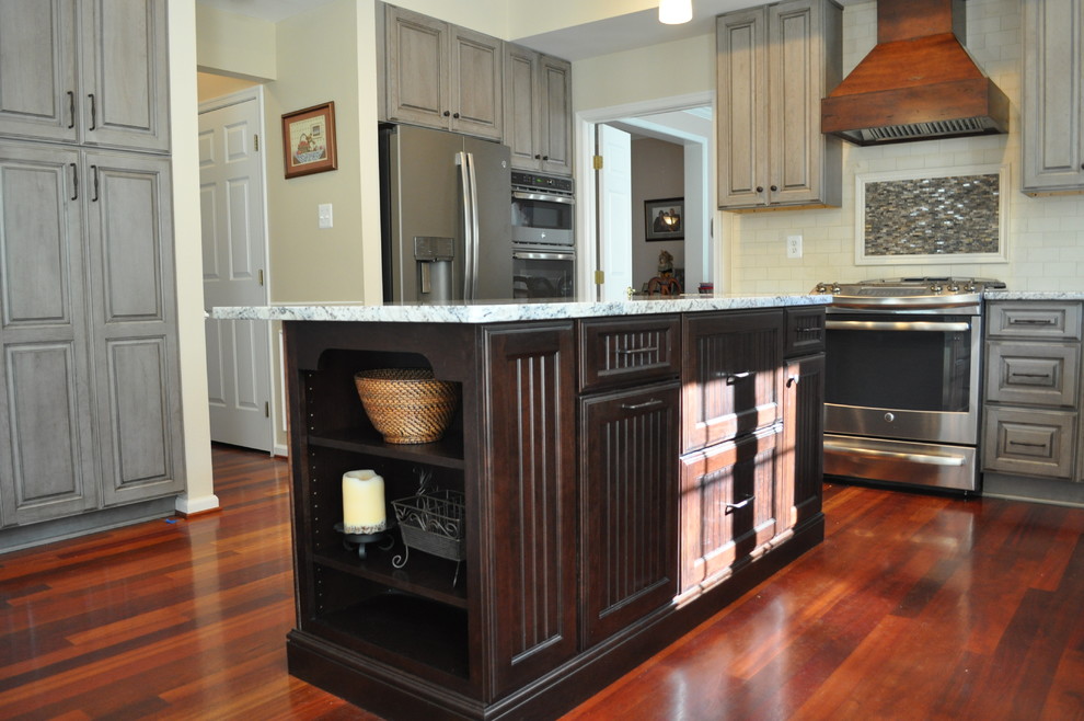 Mid-sized transitional u-shaped dark wood floor and brown floor kitchen photo in DC Metro with an undermount sink, raised-panel cabinets, beige cabinets, granite countertops, beige backsplash, stone tile backsplash, stainless steel appliances and an island