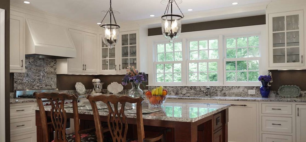 Exempel på ett mellanstort klassiskt flerfärgad flerfärgat kök, med en undermonterad diskho, vita skåp, granitbänkskiva, grått stänkskydd, stänkskydd i sten, integrerade vitvaror, mellanmörkt trägolv, en köksö, brunt golv och luckor med infälld panel