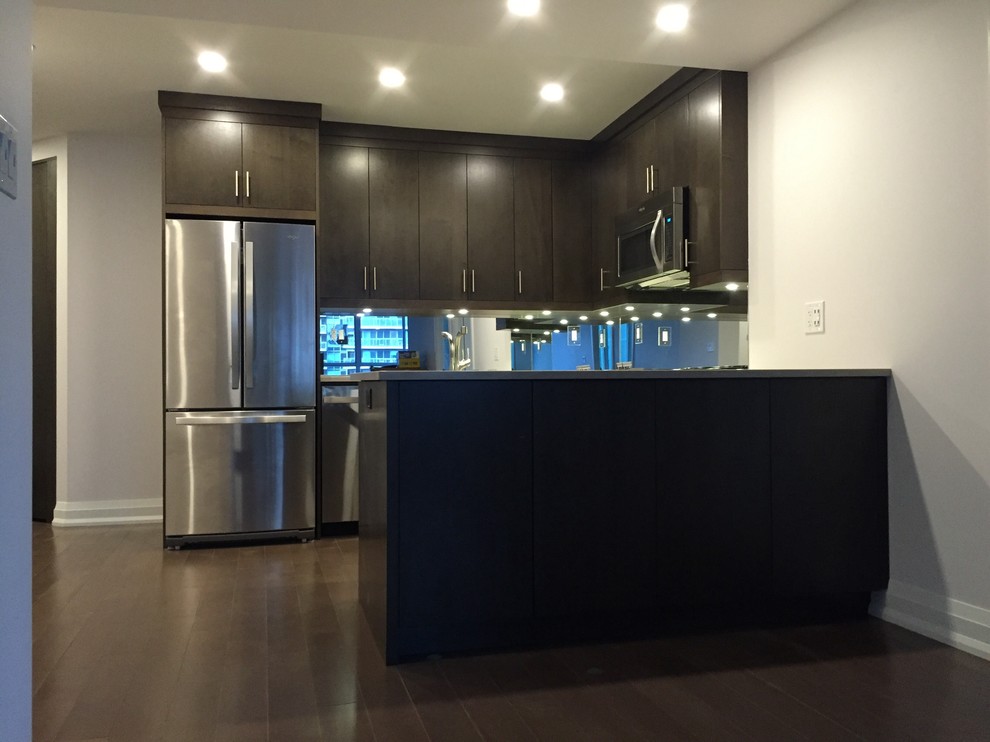Open concept kitchen - mid-sized traditional u-shaped dark wood floor open concept kitchen idea in Toronto with an undermount sink, flat-panel cabinets, dark wood cabinets, marble countertops, mirror backsplash, stainless steel appliances and a peninsula