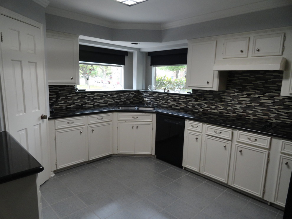 Inredning av ett modernt mellanstort kök, med en undermonterad diskho, luckor med infälld panel, vita skåp, granitbänkskiva, flerfärgad stänkskydd, svarta vitvaror och klinkergolv i keramik