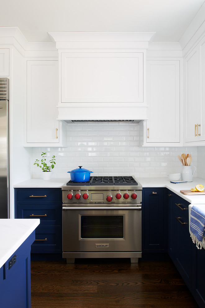 Idéer för mellanstora vintage vitt kök, med en rustik diskho, luckor med infälld panel, blå skåp, vitt stänkskydd, stänkskydd i tunnelbanekakel, rostfria vitvaror, mörkt trägolv och en köksö