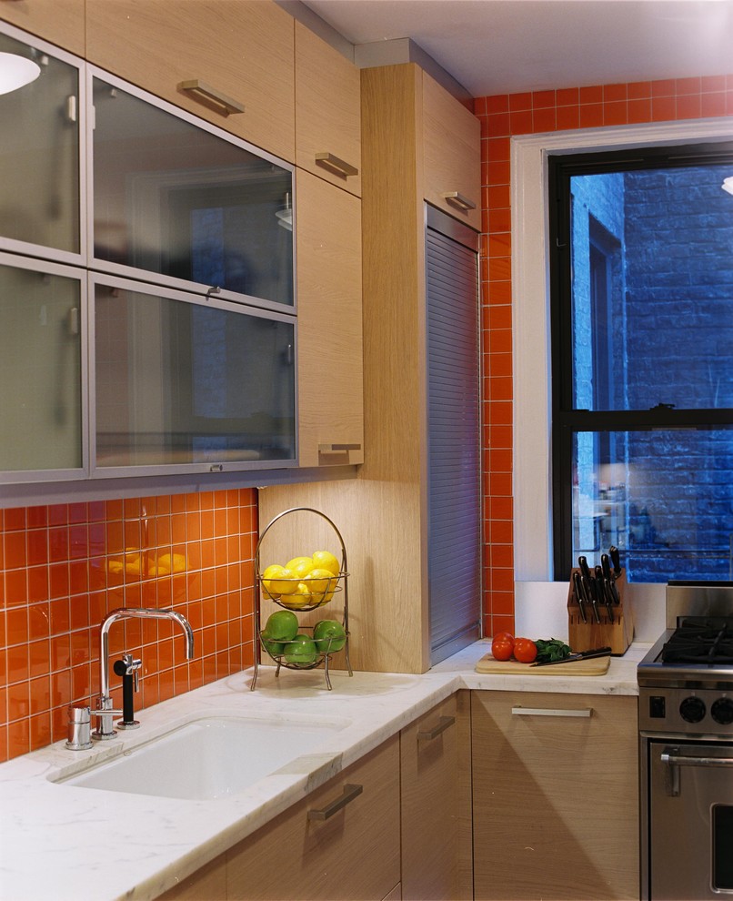ニューヨークにある小さなモダンスタイルのおしゃれなL型キッチン (シングルシンク、フラットパネル扉のキャビネット、淡色木目調キャビネット、赤いキッチンパネル、シルバーの調理設備) の写真