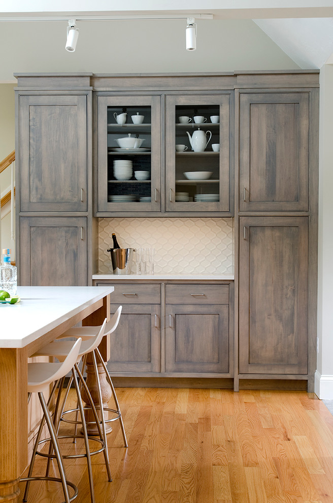 Modelo de cocina clásica renovada con armarios estilo shaker, puertas de armario de madera en tonos medios, salpicadero blanco y suelo de madera en tonos medios