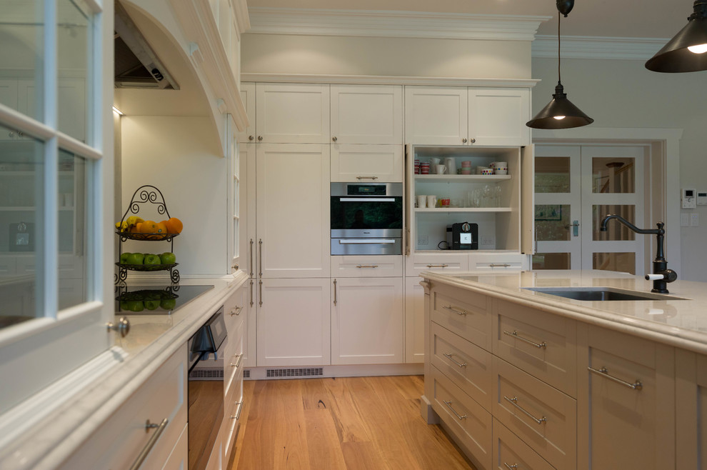 Klassische Wohnküche in L-Form mit Schrankfronten im Shaker-Stil, weißen Schränken und Kücheninsel in Sonstige