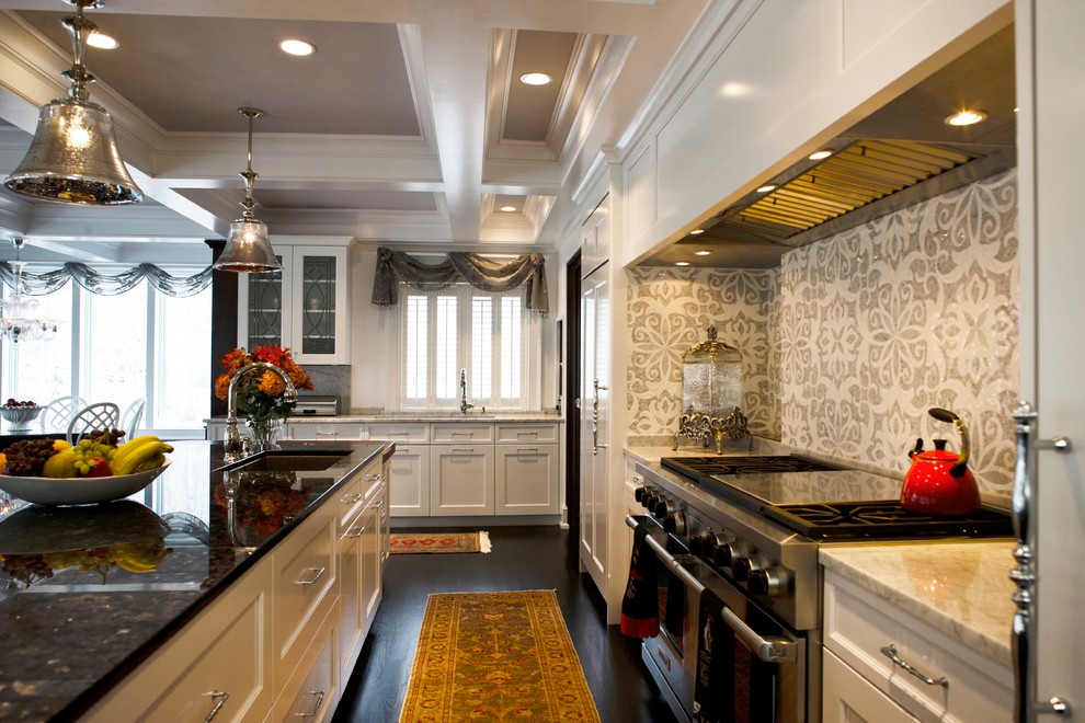 Large classic u-shaped enclosed kitchen in Philadelphia with white cabinets, marble worktops, grey splashback, mosaic tiled splashback, integrated appliances, dark hardwood flooring and an island.