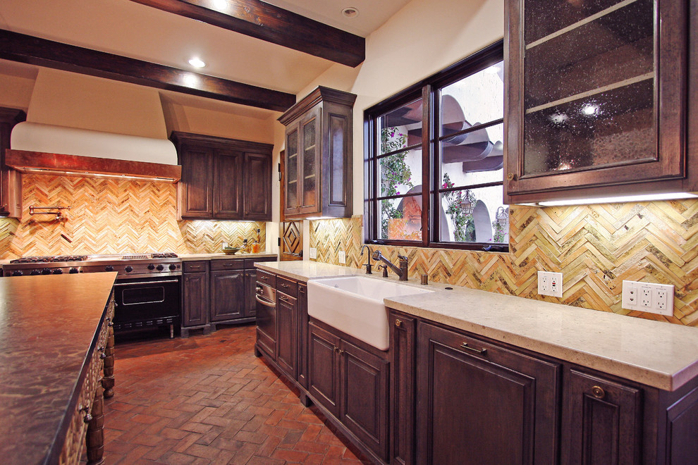 Foto på ett stort medelhavsstil kök, med en rustik diskho, luckor med upphöjd panel, skåp i slitet trä, bänkskiva i kalksten, beige stänkskydd, stänkskydd i stickkakel, integrerade vitvaror, tegelgolv och en köksö