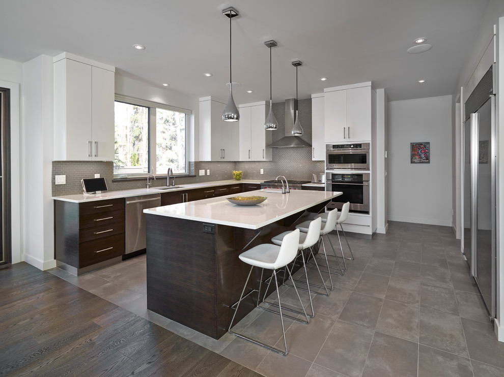 Moderne Wohnküche in U-Form mit Unterbauwaschbecken, flächenbündigen Schrankfronten, weißen Schränken, Küchenrückwand in Grau und Küchengeräten aus Edelstahl in Edmonton