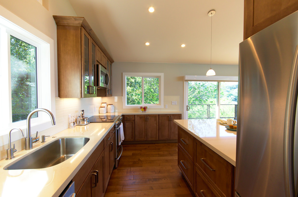 Inspiration for a small transitional galley medium tone wood floor open concept kitchen remodel in San Francisco with a single-bowl sink, shaker cabinets, medium tone wood cabinets, quartz countertops, white backsplash, porcelain backsplash and stainless steel appliances