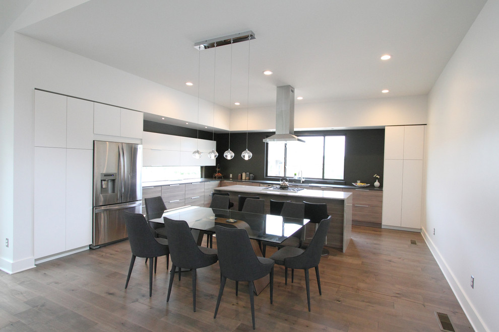Ejemplo de cocina comedor moderna grande con electrodomésticos de acero inoxidable, suelo de madera clara y una isla