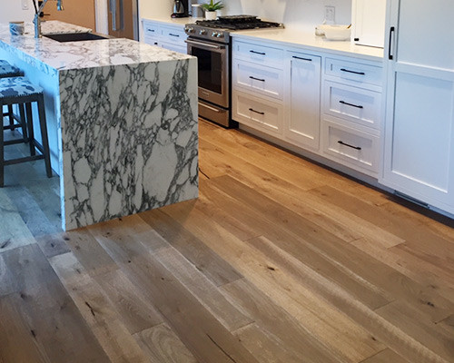 Inspiration for a contemporary kitchen in Los Angeles with marble worktops, white splashback, stainless steel appliances, light hardwood flooring and an island.