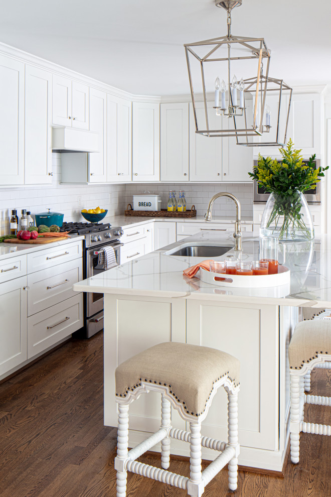 Bild på ett litet vintage vit vitt kök, med en nedsänkt diskho, luckor med infälld panel, vita skåp, bänkskiva i kvarts, vitt stänkskydd, stänkskydd i keramik, rostfria vitvaror, mörkt trägolv, en köksö och brunt golv