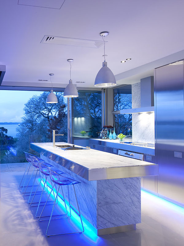 Cette image montre une grande cuisine américaine parallèle design avec un placard à porte plane, un plan de travail en inox, une crédence en marbre, un électroménager en acier inoxydable et îlot.