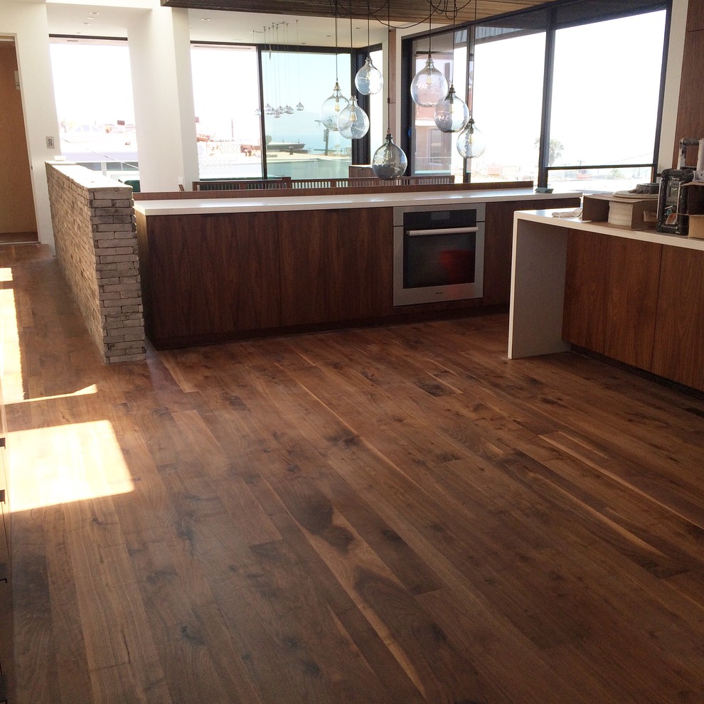 Exempel på ett mellanstort modernt kök, med släta luckor, skåp i mörkt trä, bänkskiva i kvarts, rostfria vitvaror, mörkt trägolv, en köksö och brunt golv