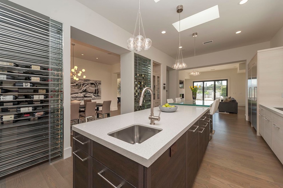 Large minimalist l-shaped medium tone wood floor and brown floor enclosed kitchen photo in Los Angeles with a double-bowl sink, flat-panel cabinets, white cabinets, quartz countertops, beige backsplash, matchstick tile backsplash, stainless steel appliances and an island