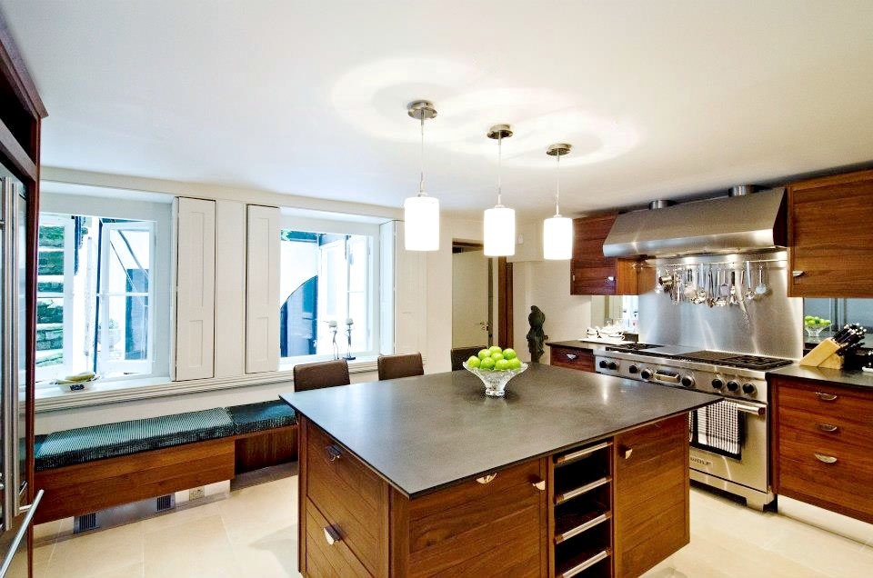 Foto på ett stort funkis kök och matrum, med granitbänkskiva, stänkskydd med metallisk yta, spegel som stänkskydd, rostfria vitvaror, kalkstensgolv och en köksö