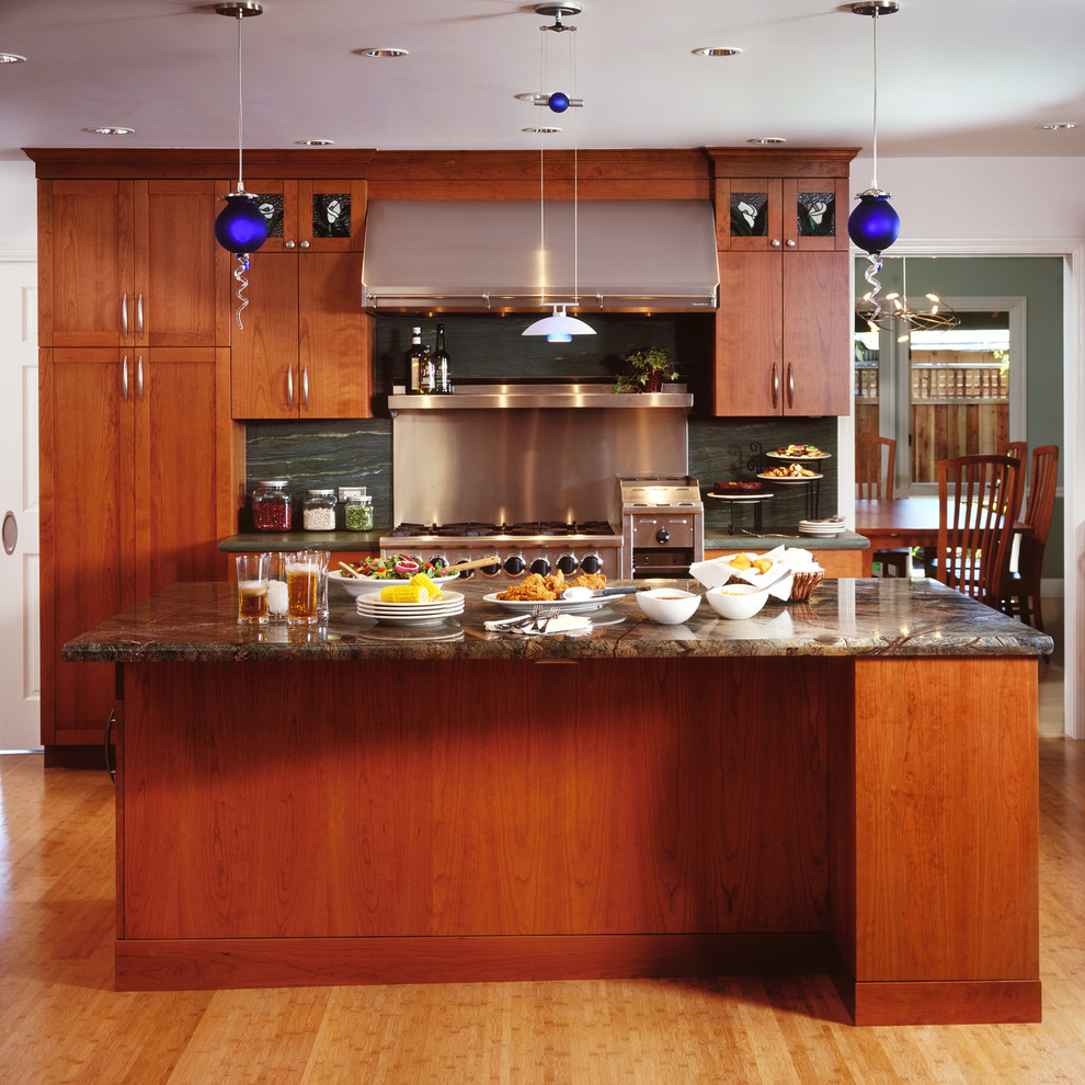Foto di una cucina minimal con elettrodomestici in acciaio inossidabile, ante in legno scuro, paraspruzzi verde e paraspruzzi in lastra di pietra