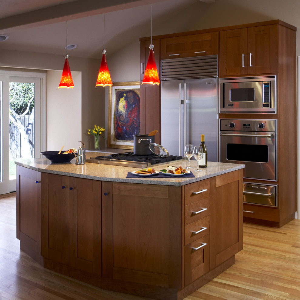 Foto de cocina contemporánea con electrodomésticos de acero inoxidable, armarios estilo shaker y puertas de armario de madera en tonos medios