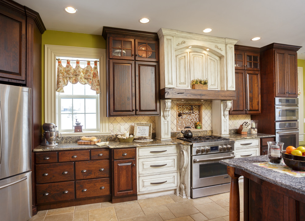 Example of a large cottage l-shaped ceramic tile eat-in kitchen design in Philadelphia with an undermount sink, raised-panel cabinets, distressed cabinets, granite countertops, beige backsplash, stone tile backsplash, stainless steel appliances and an island