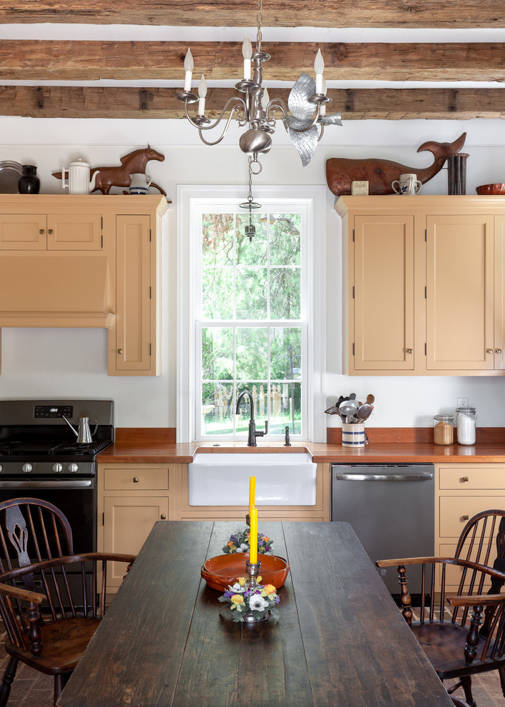 Inspiration for a small country single-wall brick floor, brown floor and exposed beam eat-in kitchen remodel in Raleigh with a farmhouse sink, shaker cabinets, orange cabinets, stainless steel appliances, orange countertops, wood countertops and no island