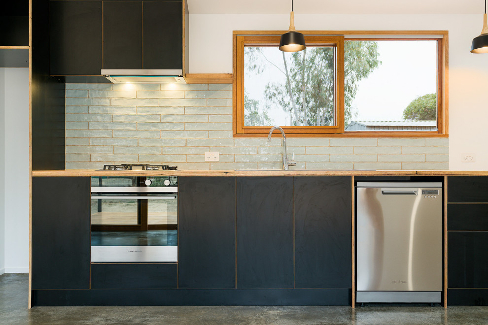 Diseño de cocina lineal actual de tamaño medio abierta con puertas de armario negras, encimera de madera y salpicadero de azulejos de porcelana