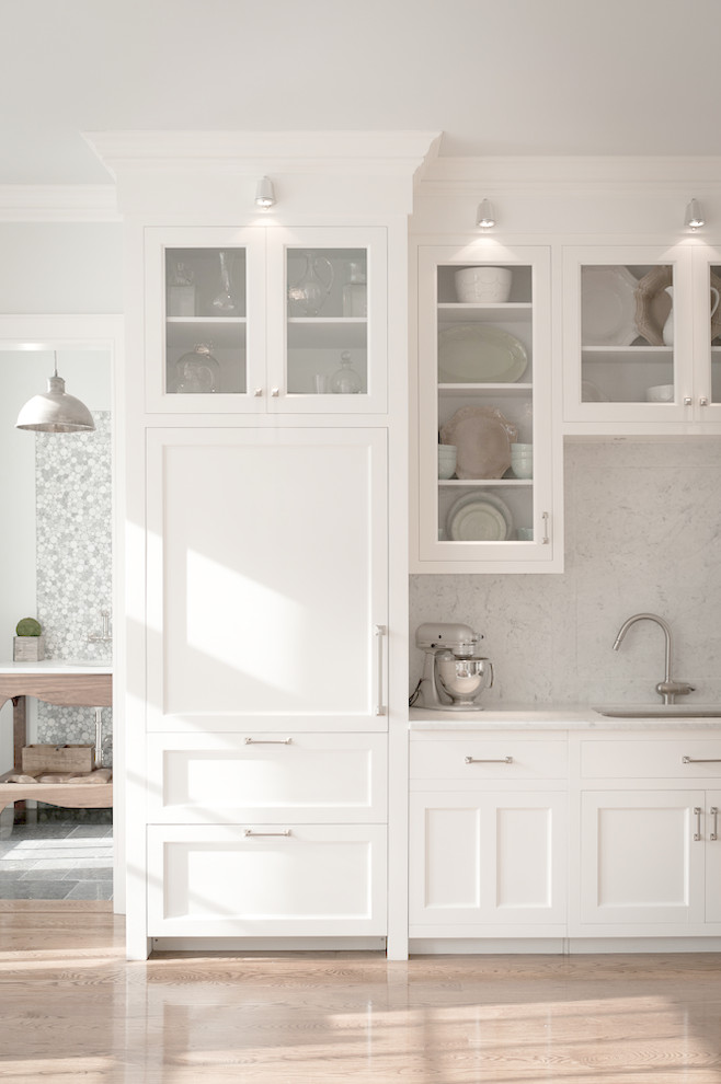 Inspiration for a classic kitchen in New York with glass-front cabinets, a submerged sink, white cabinets, white splashback, stone slab splashback and integrated appliances.