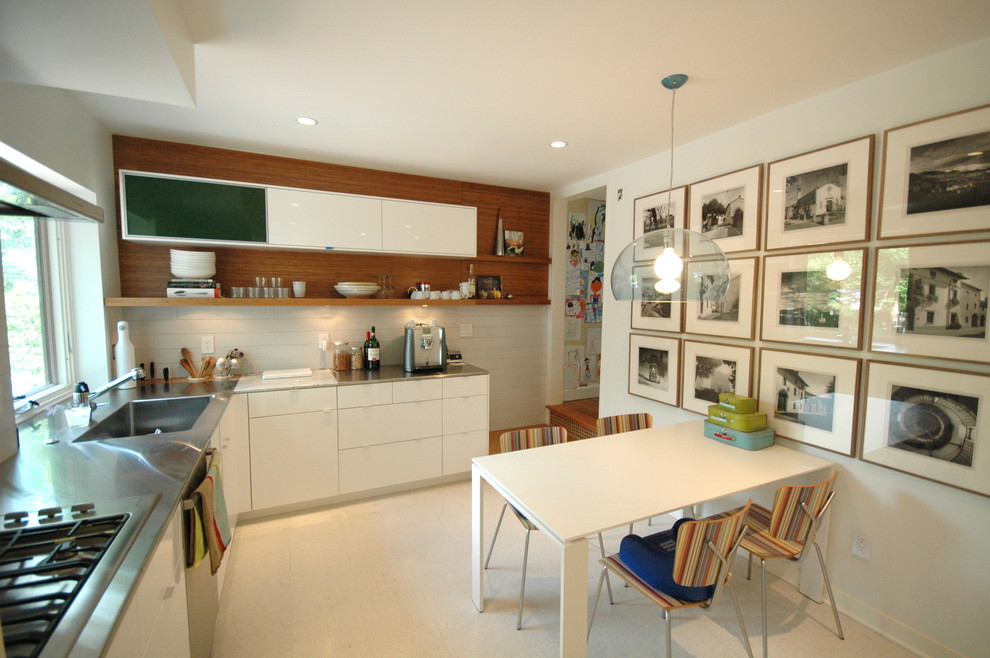 Стильный дизайн: глянцевая кухня в современном стиле с столешницей из нержавеющей стали, монолитной мойкой, плоскими фасадами и белыми фасадами - последний тренд