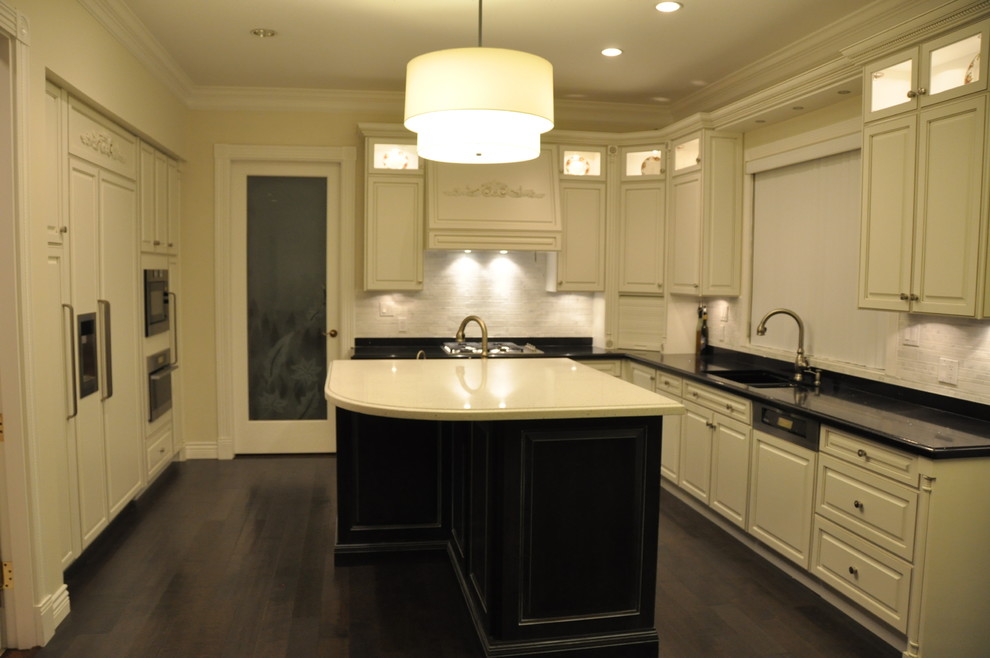 Exempel på ett avskilt, mellanstort klassiskt u-kök, med en undermonterad diskho, luckor med upphöjd panel, bänkskiva i kvartsit, vitt stänkskydd, stänkskydd i stenkakel, rostfria vitvaror, mörkt trägolv och en köksö