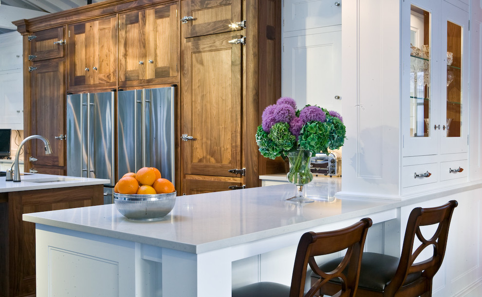 Imagen de cocina actual con electrodomésticos de acero inoxidable, puertas de armario de madera oscura y barras de cocina