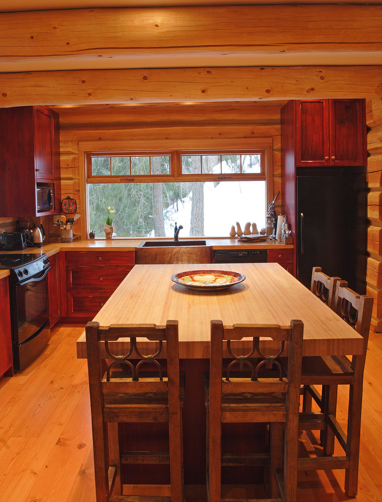 Exempel på ett rustikt kök, med träbänkskiva, svarta vitvaror och skåp i mörkt trä