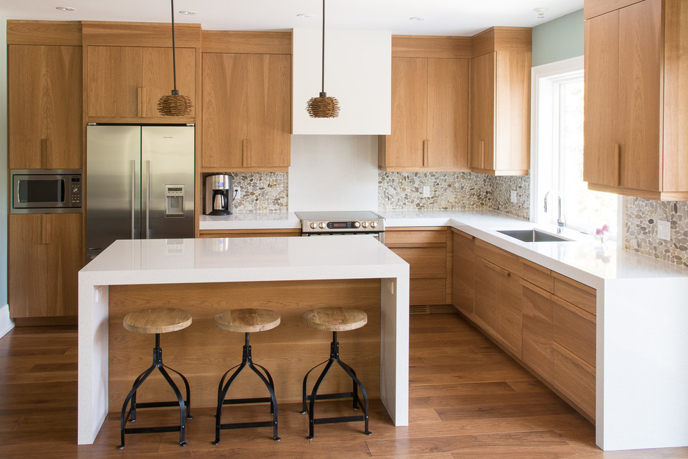 Klassische Küche in L-Form mit Unterbauwaschbecken, flächenbündigen Schrankfronten, hellbraunen Holzschränken, Küchengeräten aus Edelstahl, braunem Holzboden und Kücheninsel in Burlington