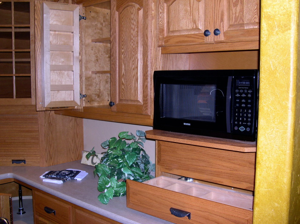 Photo of a small bohemian l-shaped kitchen/diner in Milwaukee with a double-bowl sink, raised-panel cabinets, medium wood cabinets, composite countertops, black splashback, black appliances, terracotta flooring and an island.